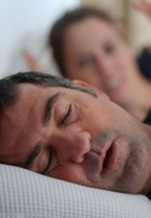 Closeup of snoring man sleeping next to annoyed partner