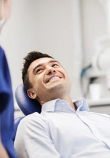 Man smiling at dental assistant while sitting in treatment chair